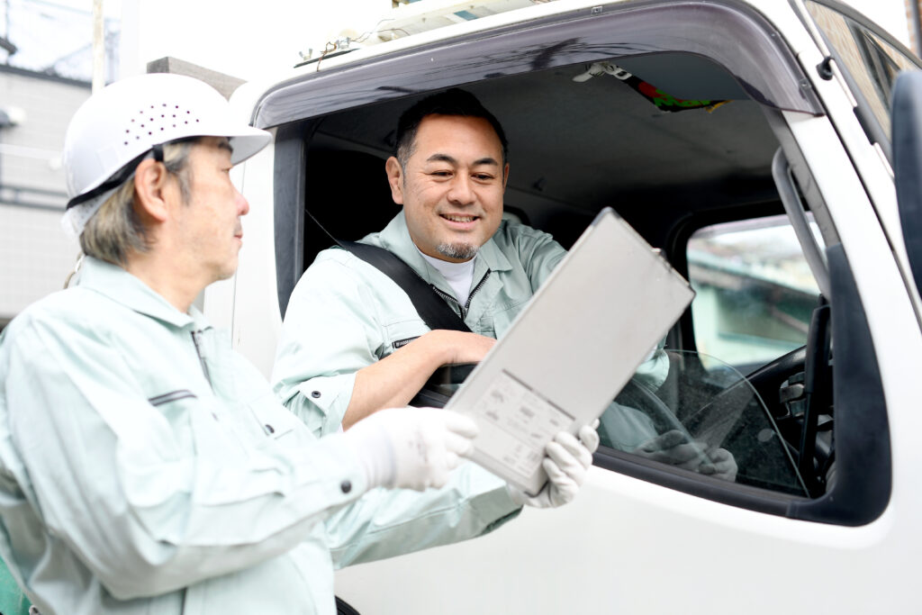 会話をするトラックに乗る作業服を着た人の画像
